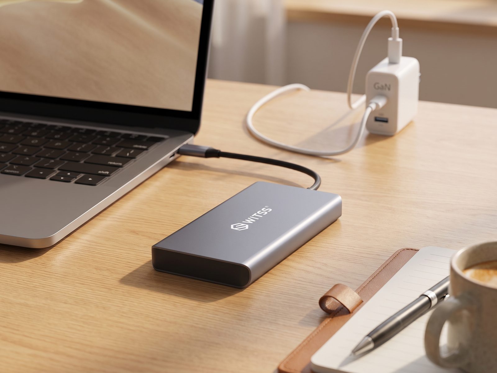 Hub Switss® 12-en-1 sur un bureau, câble de charge de l'ordinateur portable relié à un chargeur GaN en arrière-plan