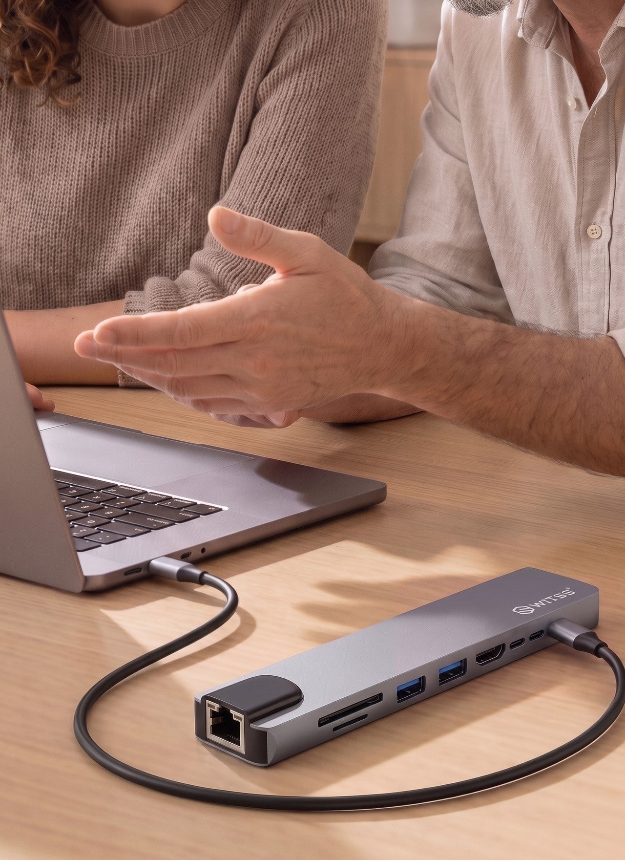 Deux personnes travaillent sur un ordinateur portable relié via un hub USB-C 8-en-1 Switss®