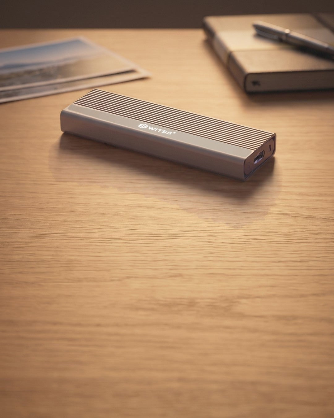 Switss® M.2 SSD enclosure on a desk next to printed family photos