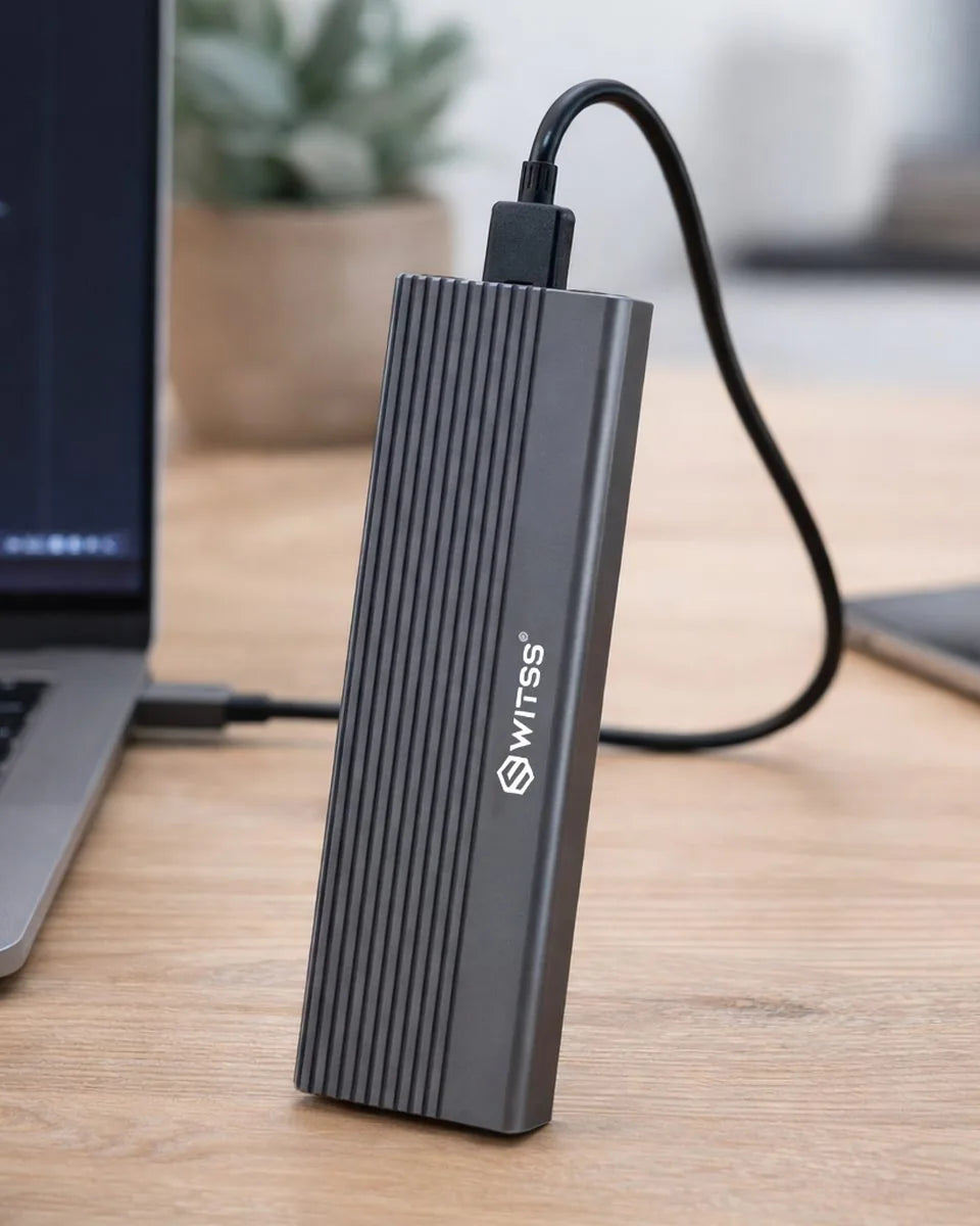 Boîtier SSD M.2 Switss posé debout sur un bureau, câble branché à un ordinateur portable