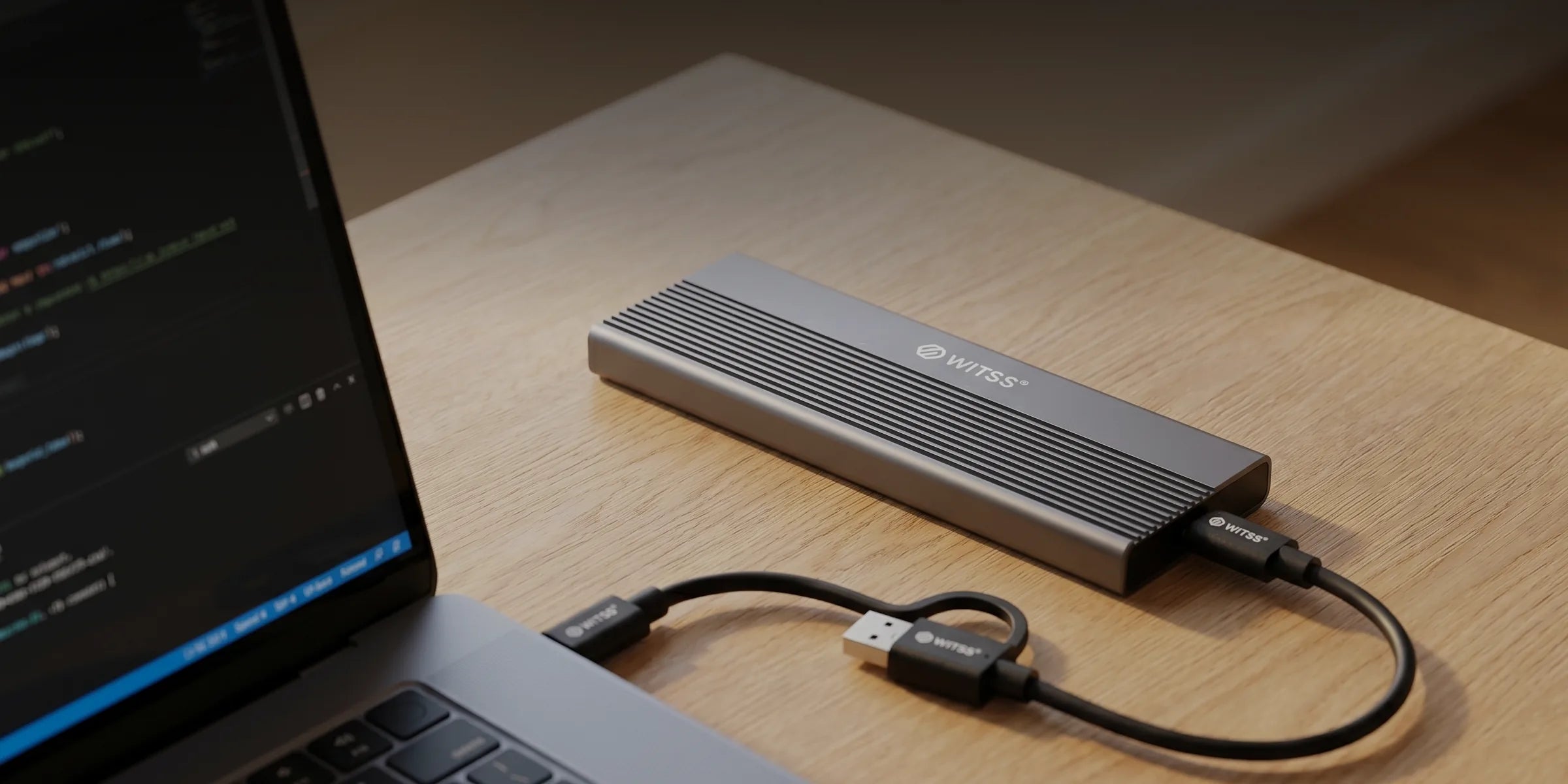 Le boîtier M.2 sur un bureau en bois, relié à un ordinateur portable par le câble USB-C, en lumière du soir