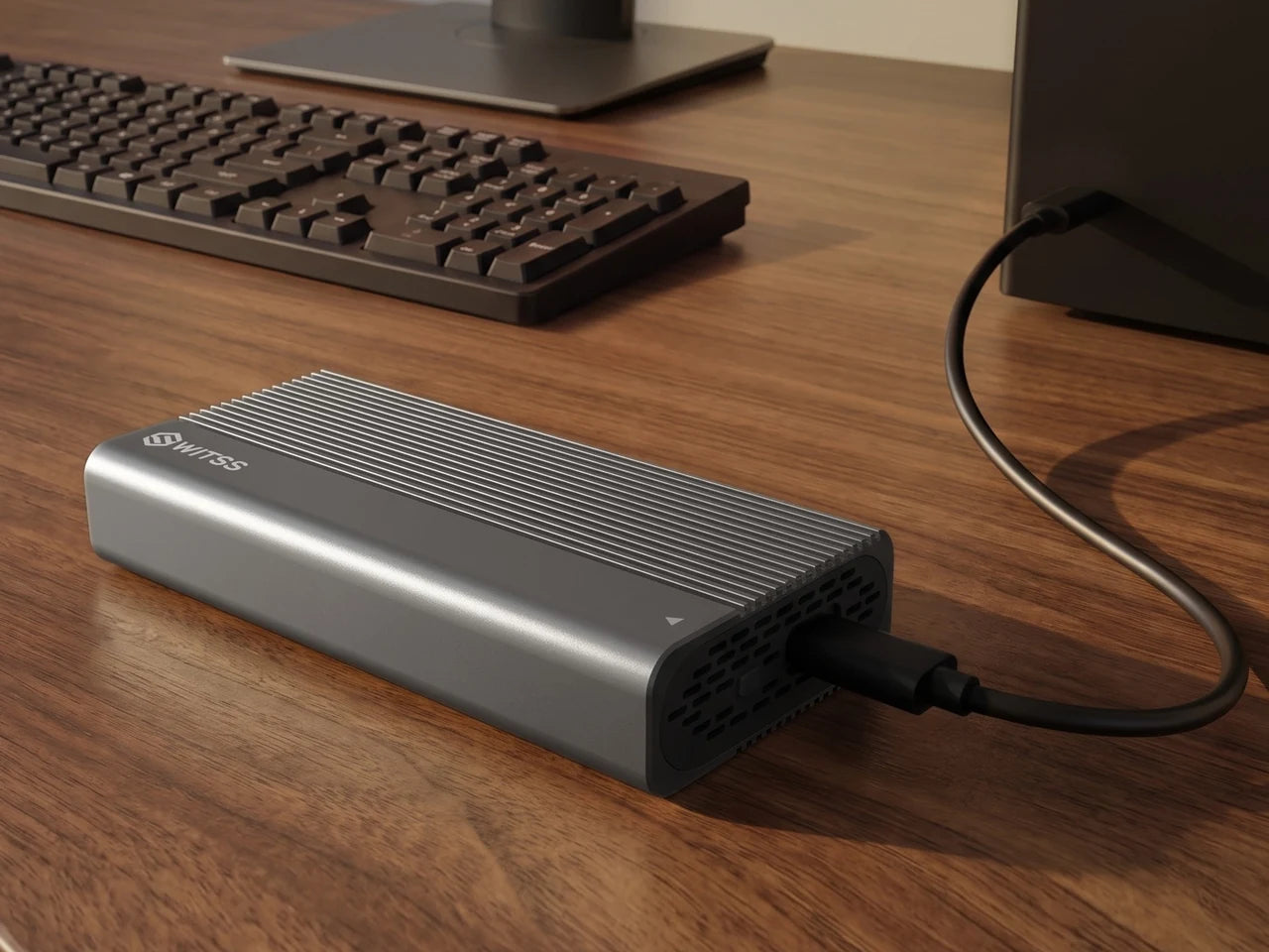 Le boîtier M.2 Switss sur un bureau en bois, avec le câble USB-C relié au port USB d’un PC
